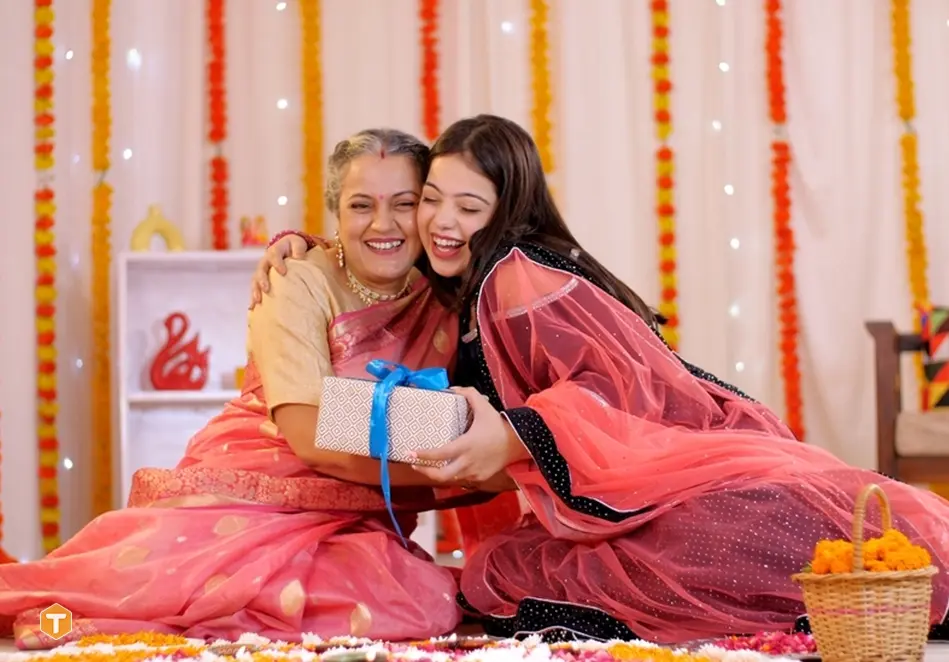 دو زن هندی خندان با لباس محلی و یک جعبه کادو با روبان آبی