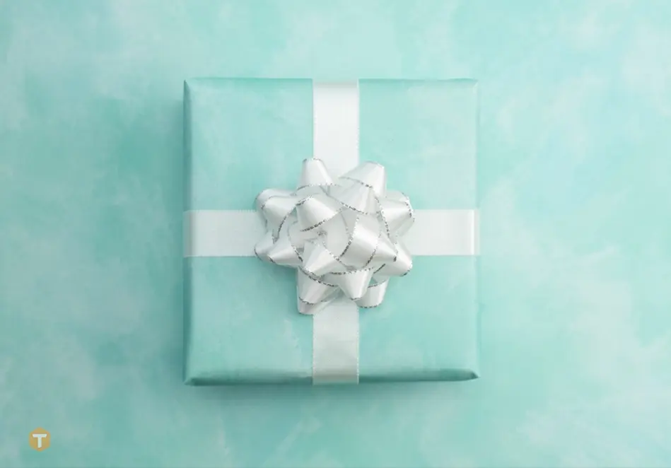 یک جعبه سبز رنگ هدیه با روبان سفید و زمینه متناسب با رنگ جعبه